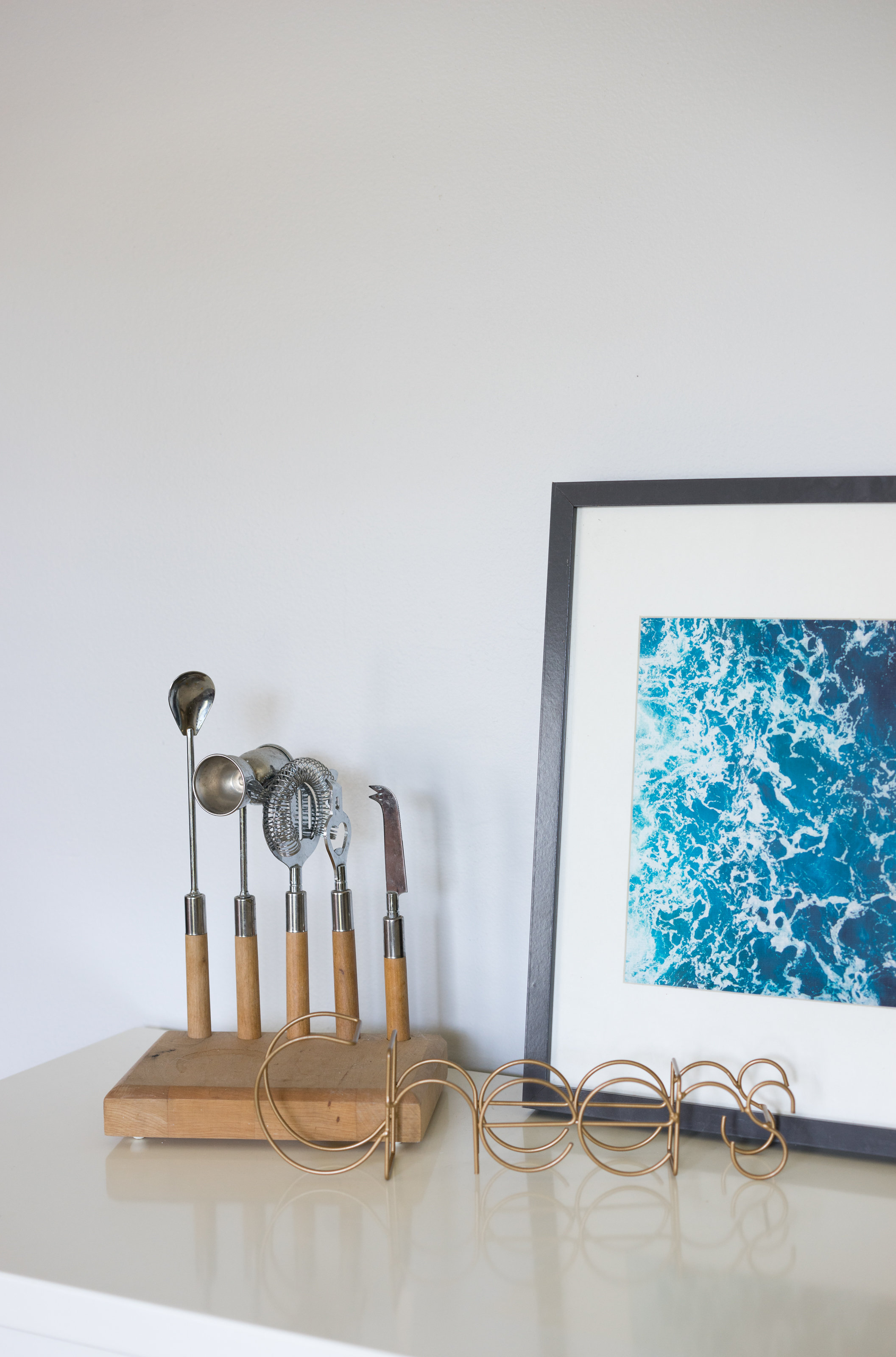 House Tour: A bar tool set and framed photo of the ocean on top of a bar cart