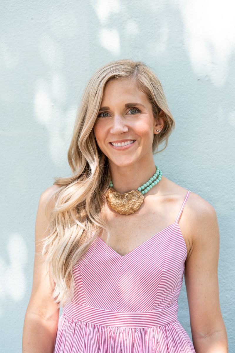 Blonde woman wearing a pink J.Crew dress and an oyster necklace