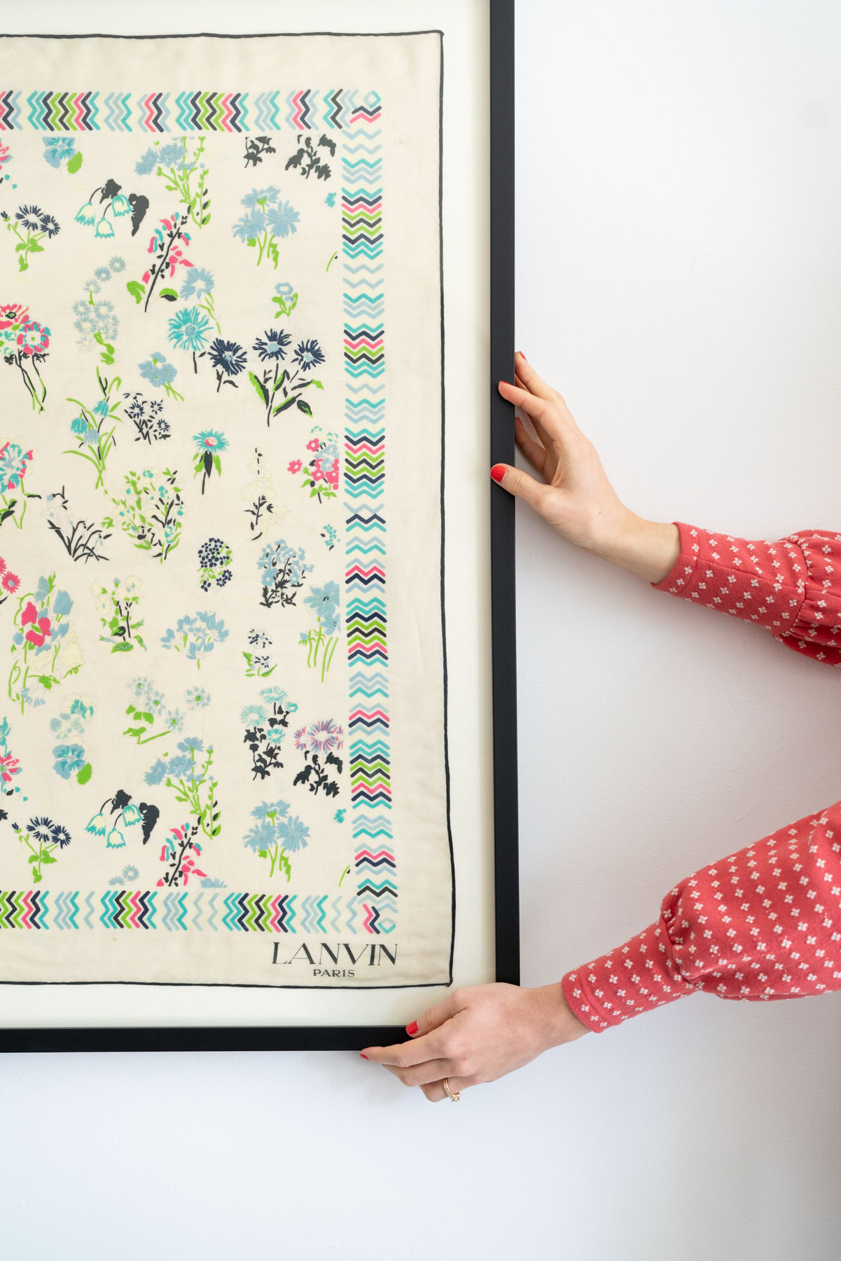 Two hands holding up a colorful, floral vintage silk scarf made by Lanvin Paris.