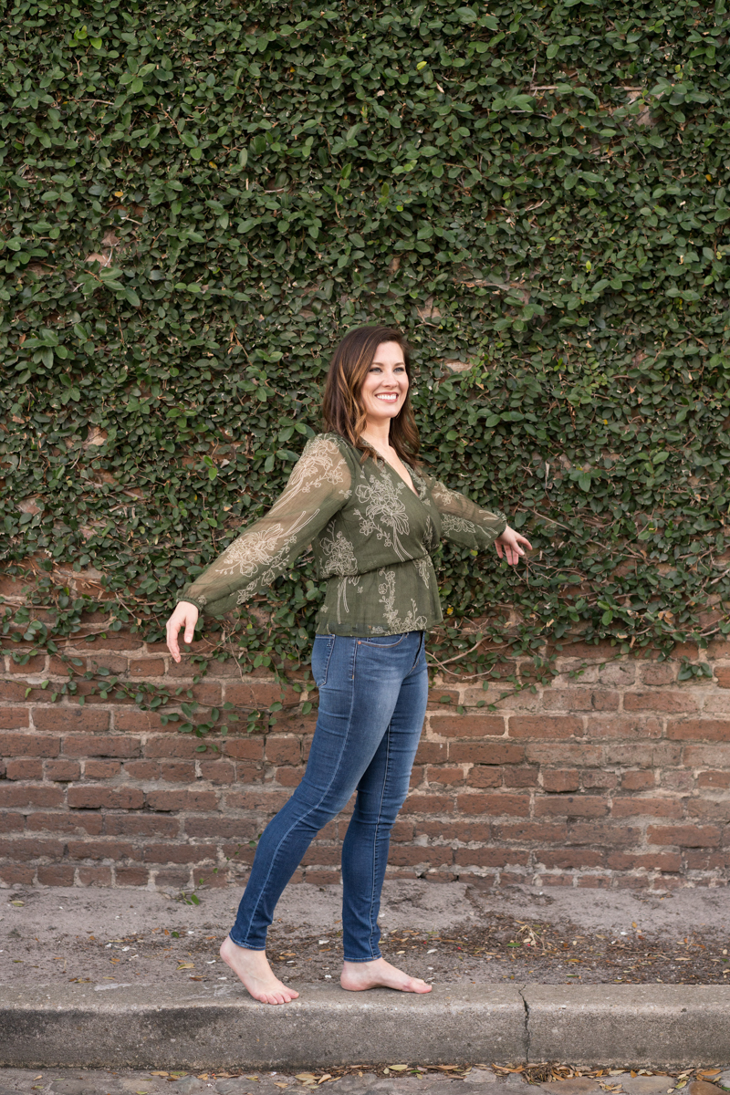 Woman entrepreneur walking along the curb of a brick and ivy wall
