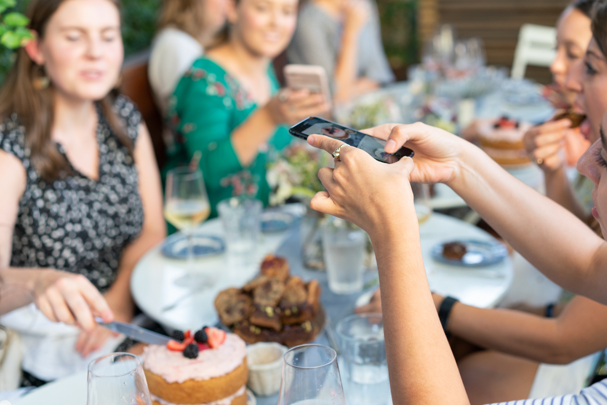 A woman taking a photo of the table at an outdoor dinner party