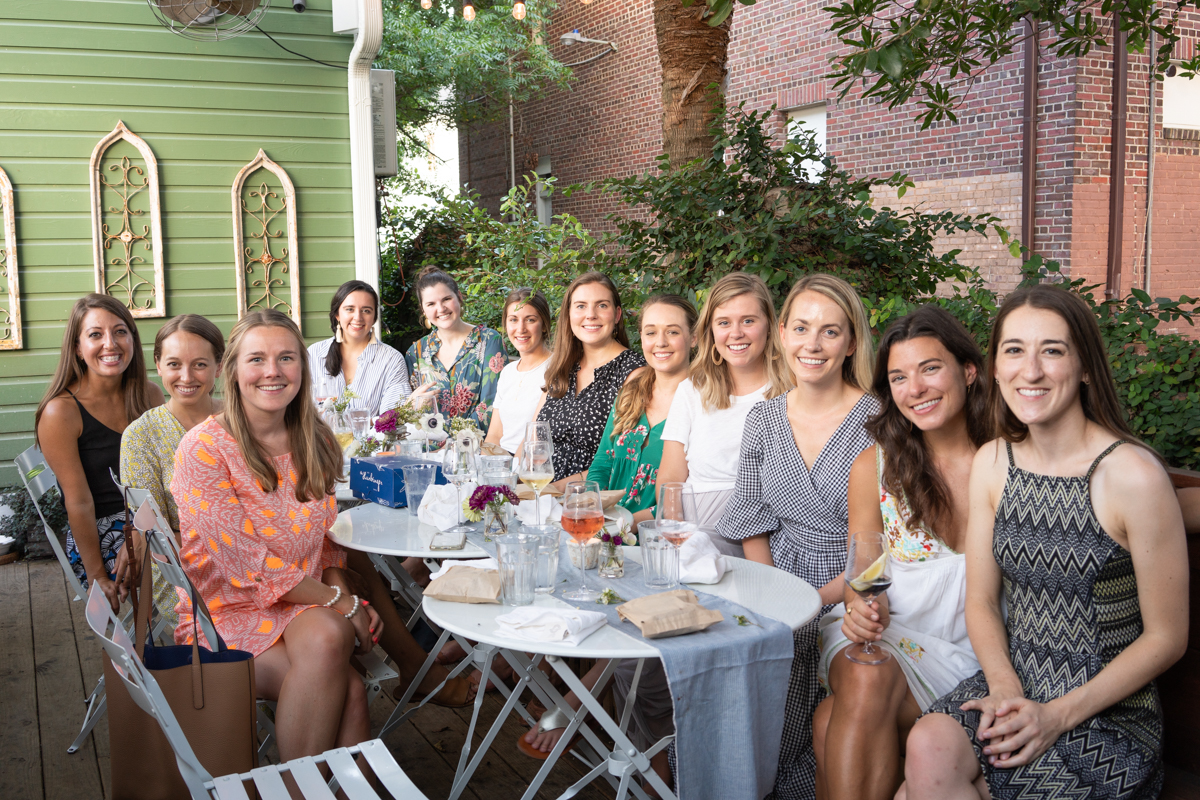A group of women smiling at the camera at an outdoor dinner party