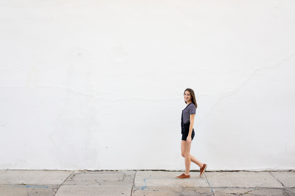Girl in overalls walking against white background