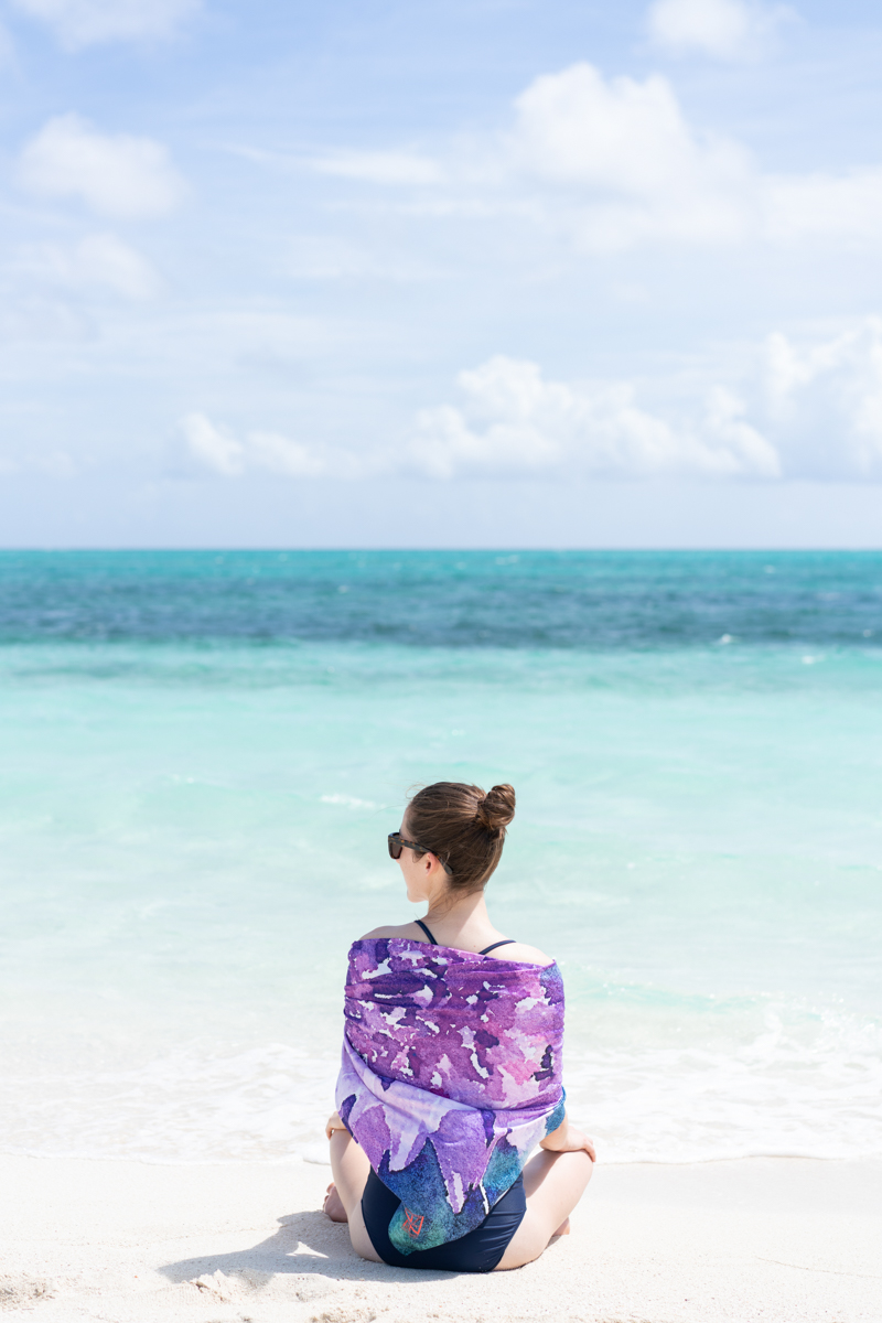 Model holding a brightly colored towel on a Turks & Caicos beach