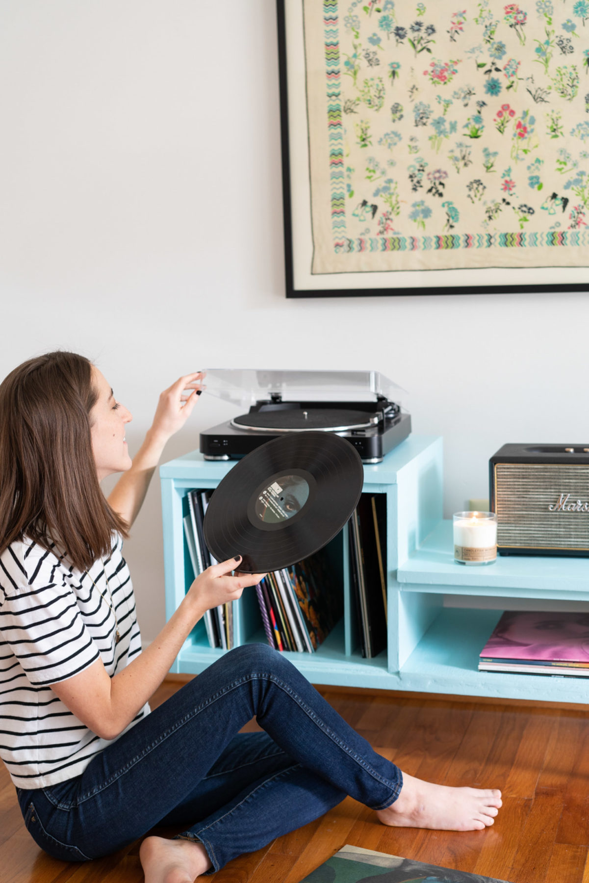 Young woman sitting on the floor and placing a record on her record player