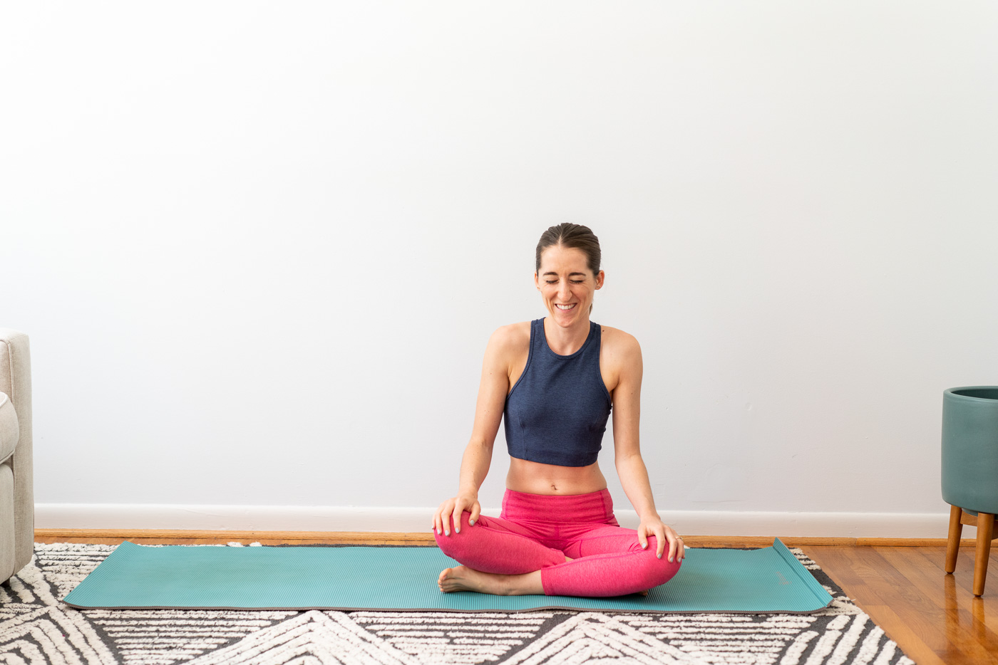 Woman in workout clothing sitting cross-legged on a yoga mat