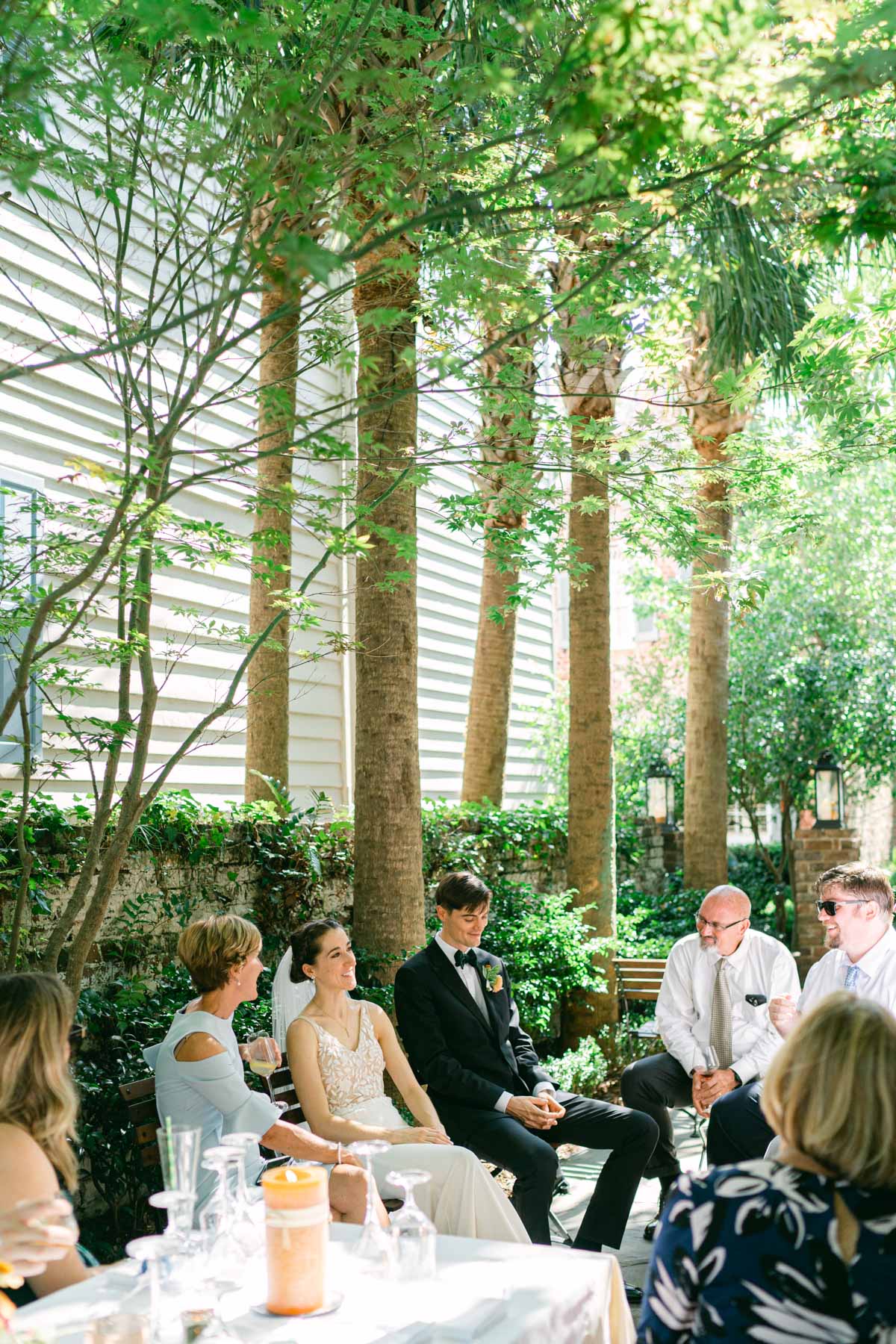 A bride and groom and their wedding guests gather in a courtyard for cocktail hour