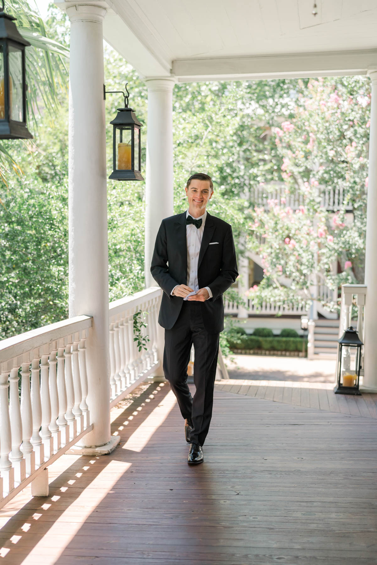 Groom in a tux walking on a porch at Zero George hotel in Charleston, SC