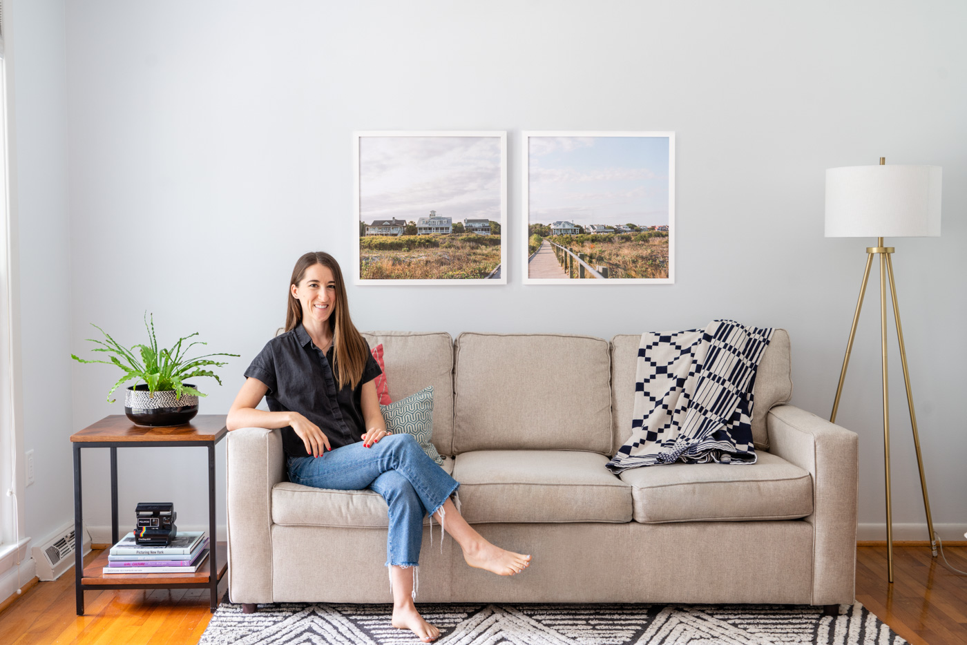 A diptych photograph of beach homes on Sullivan's Island, SC hanging over a beige couch. The photographer of the photo is sitting on the couch