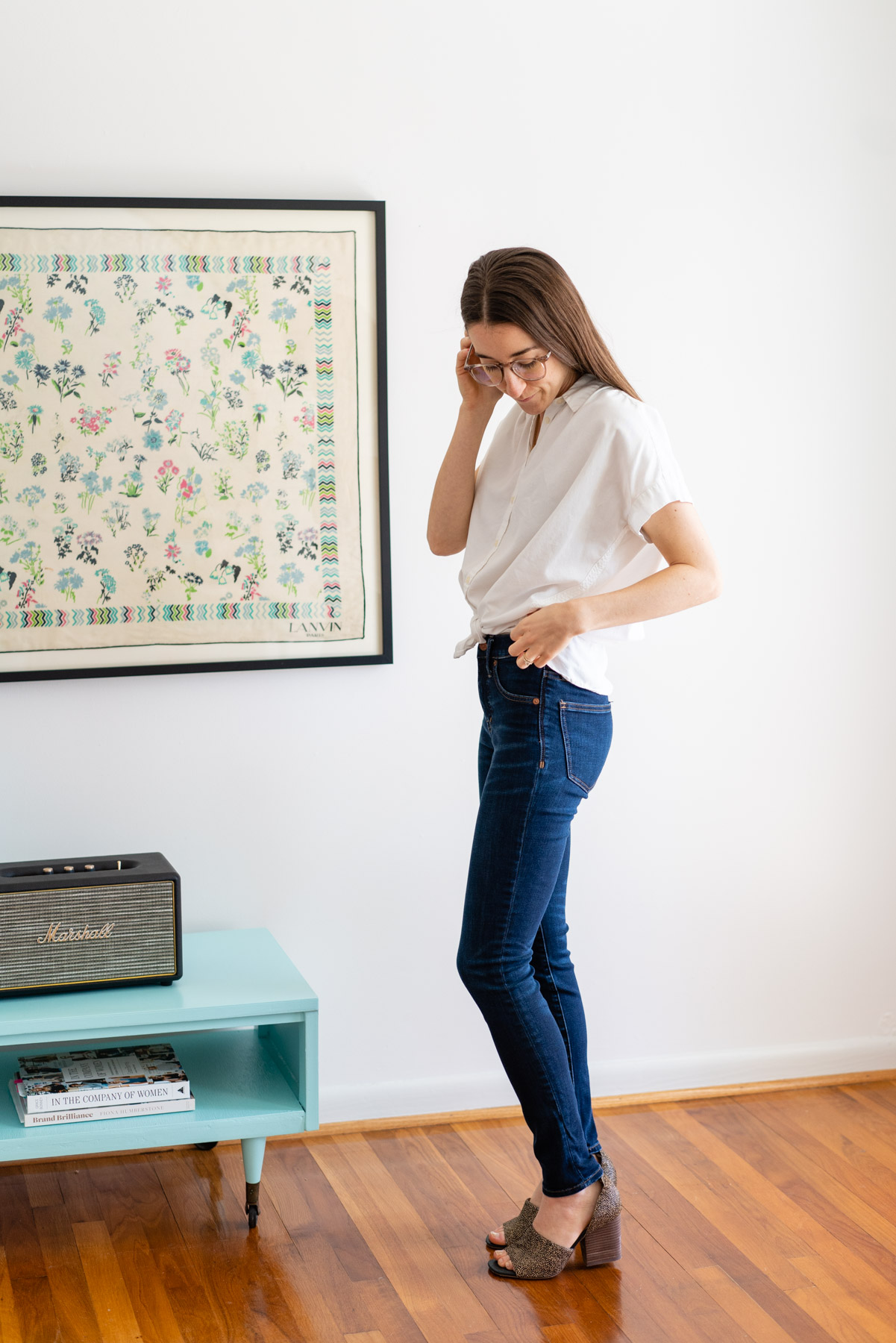 Woman modeling Madewell's dark Skinny jeans with a white button up shirt tied at the waist