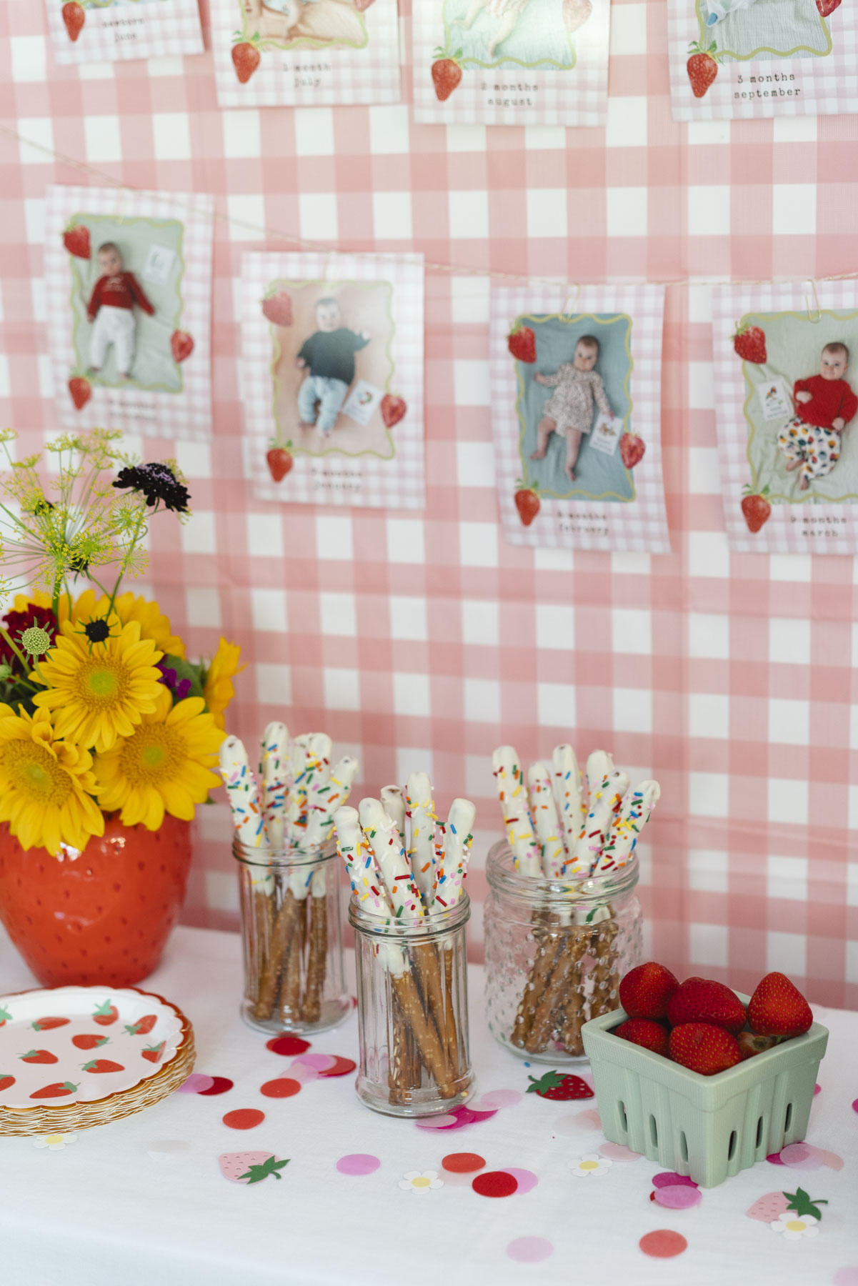 Close up of string of baby photos and three jars of chocolate-covered pretzels. 