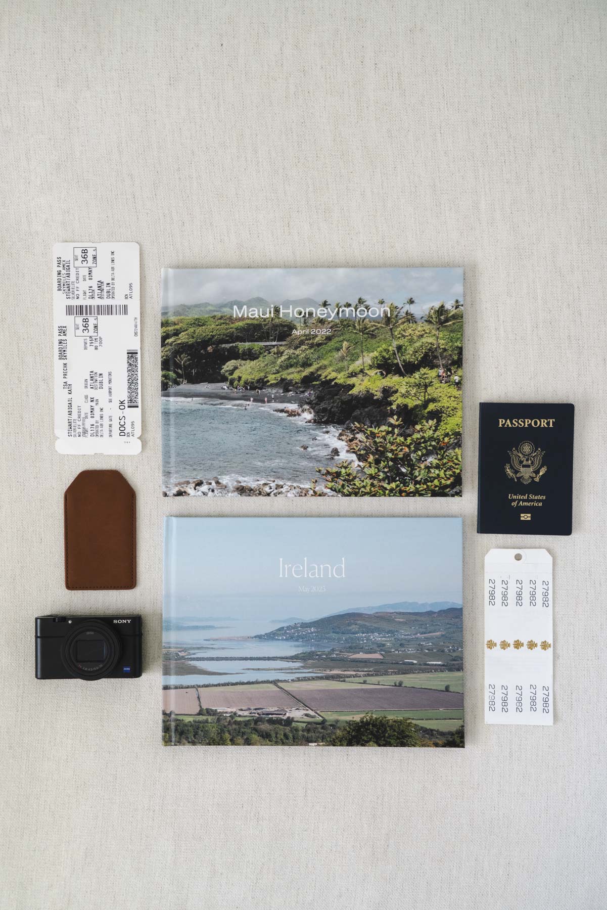 Flay lay photo of the two photo books, a passport, a camera, and two luggage tags. 