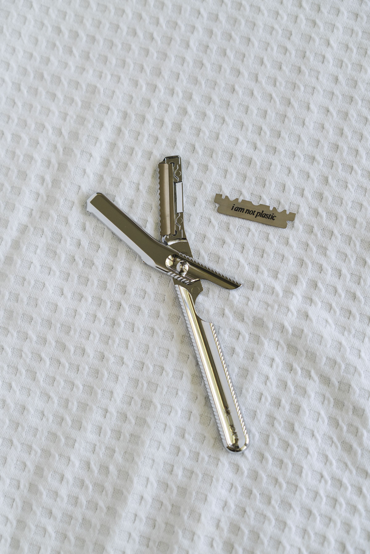 Flat lay photo of the LEAF dermaplane on top of a white, waffle textured towel. 