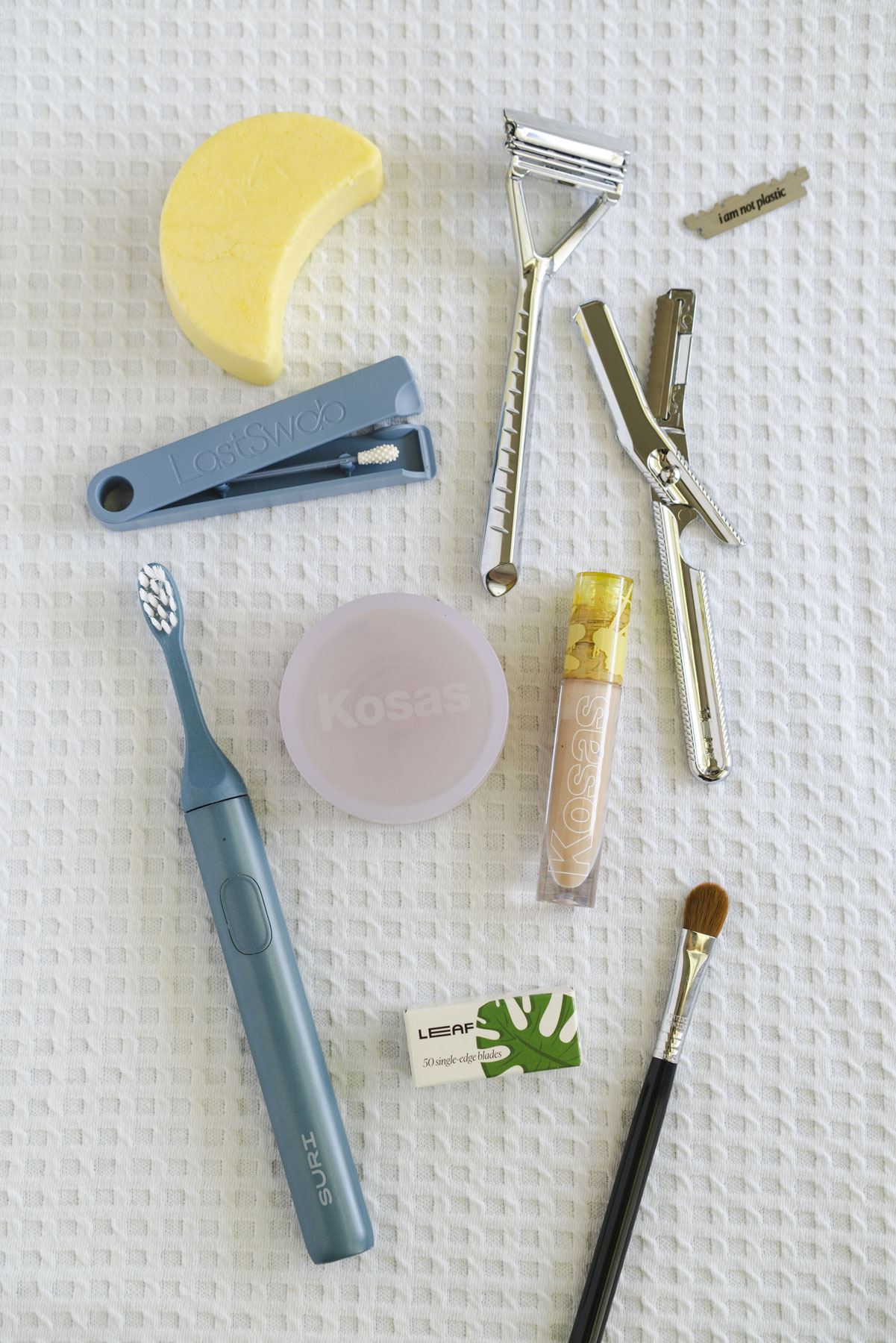 Flat lay photo of bathroom products laid out on a white, waffle textured towel. 