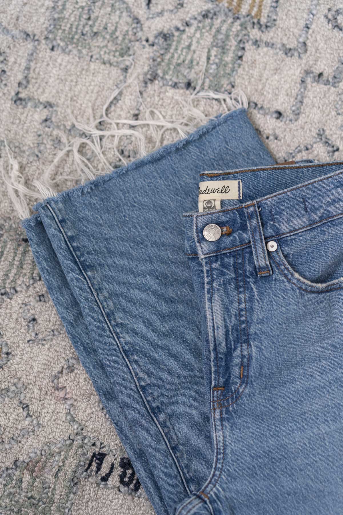 Flat view of a pair of folded blue denim jeans.