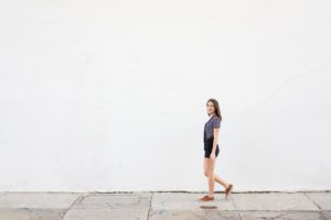 Girl walking against a white wall