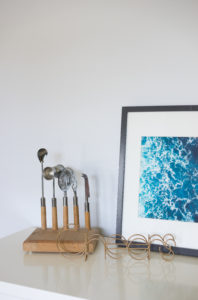 A bar tool set and framed photo of the ocean on top of a bar cart