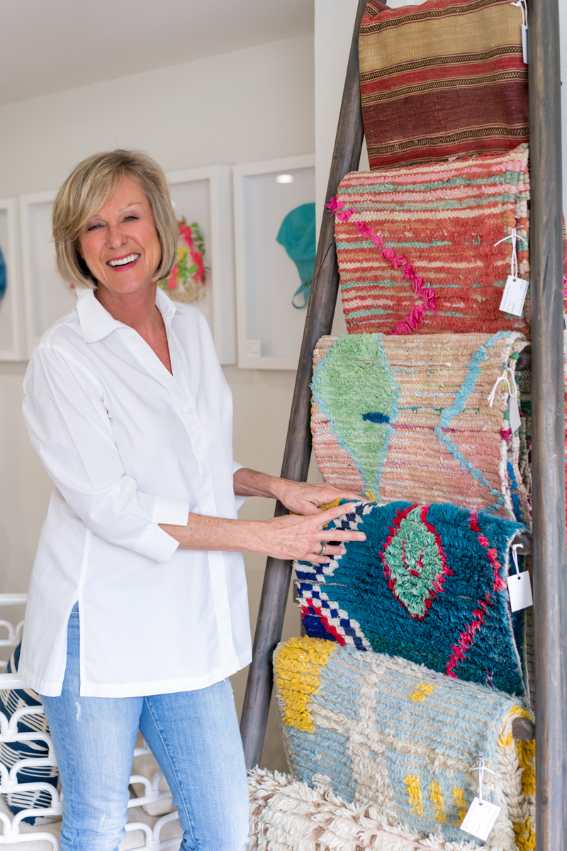 Woman interior designer smiling next to a display of rugs on a wooden ladder
