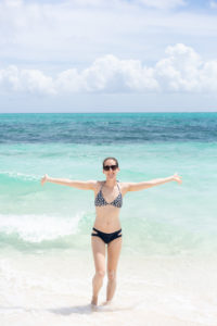 Girl standing in Turks & Caicos water with arms spread out