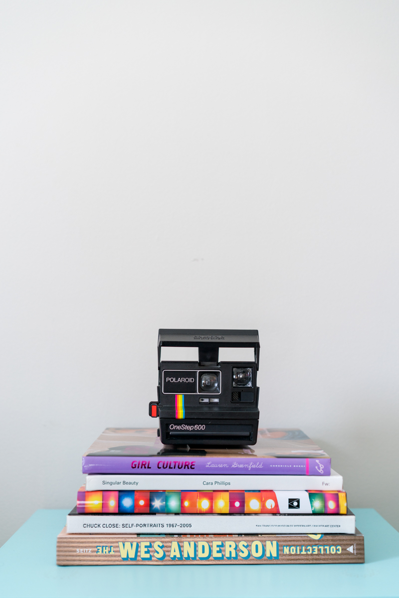 A stack of photography books with a vintage Polaroid camera on top