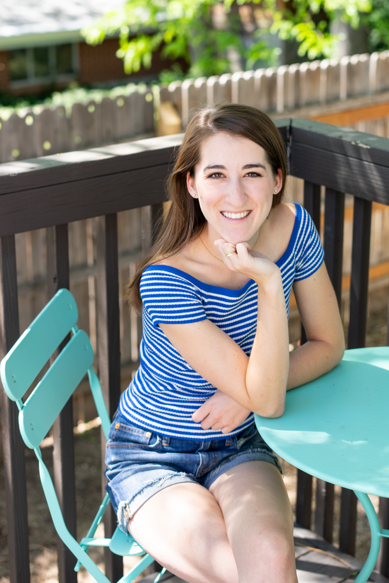 Woman wearing striped blue shirt sitting at a teal blue patio table