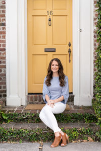 Woman sitting on the steps of a house with a yellow door
