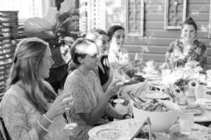 A woman toasting a group of women at an outdoor dinner