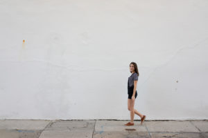 Girl in overalls walking against white background