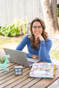 Woman sitting at a table outside with a laptop, notebook, and succulent