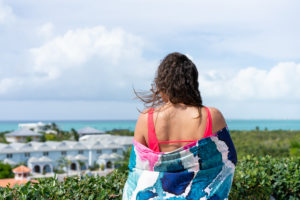 Model holding a brightly colored towel on a Turks & Caicos beach