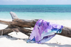 A purple towel hanging over a piece of driftwood on a Turks & Caicos beach