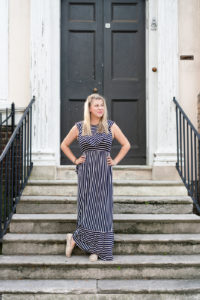 Woman standing on stairs of a historic house in a striped dress