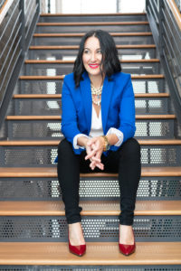 Business woman in blue blazer and red heels sitting on industrial stairs