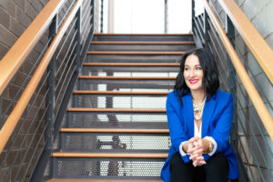 Business woman in blue blazer sitting on industrial stairs