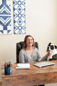 Woman sitting at desk with her dog jumping up next to her