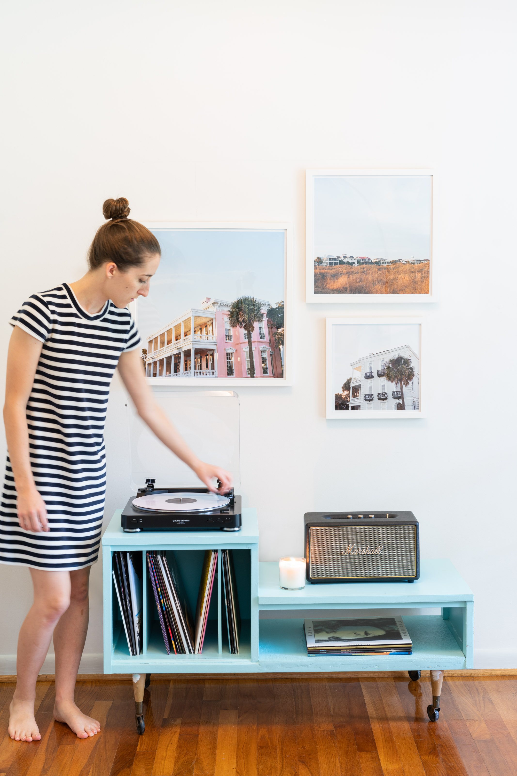 Woman placing a needing on a turntable on top of a record player table 