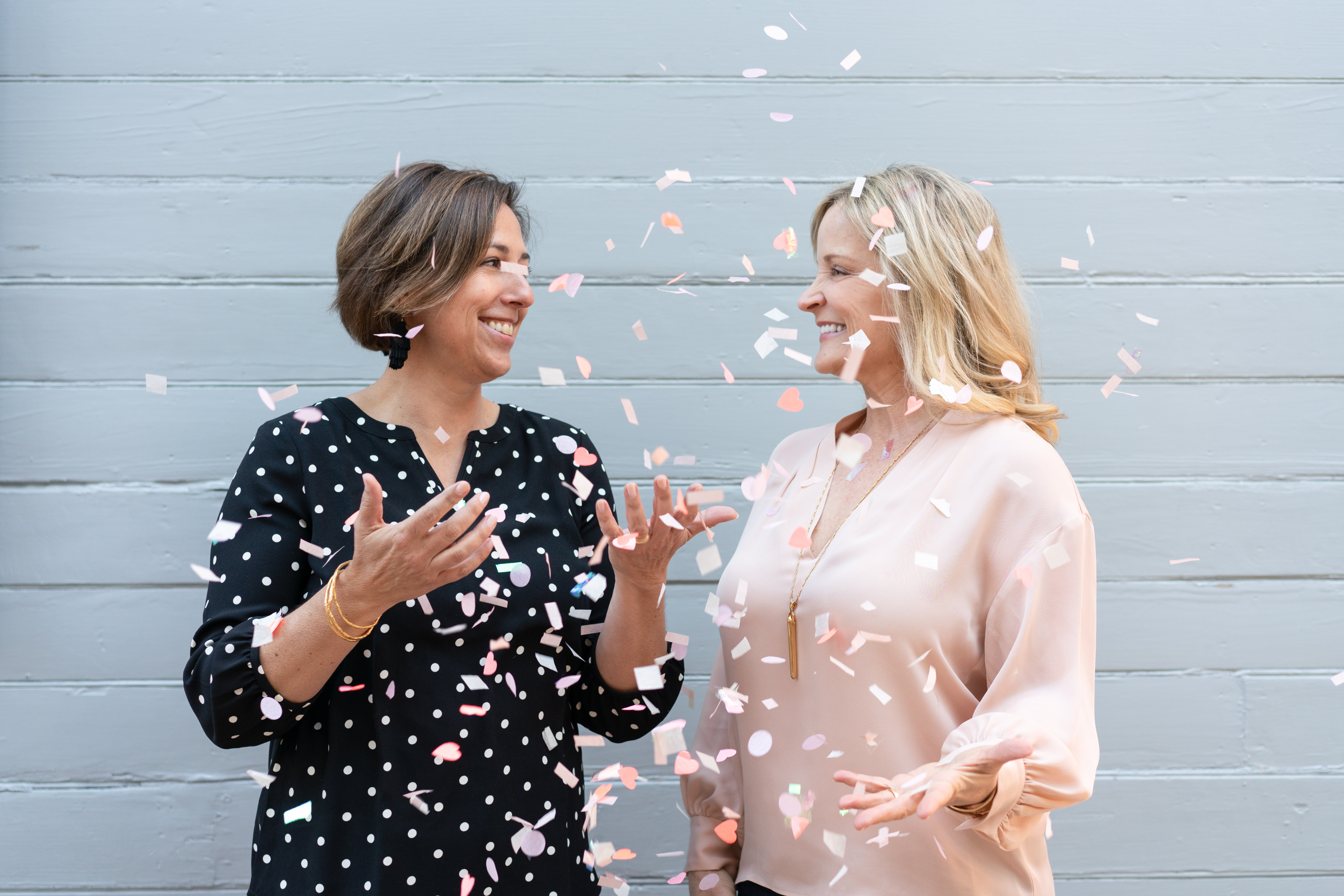 Two women throwing confetti and smiling at each other