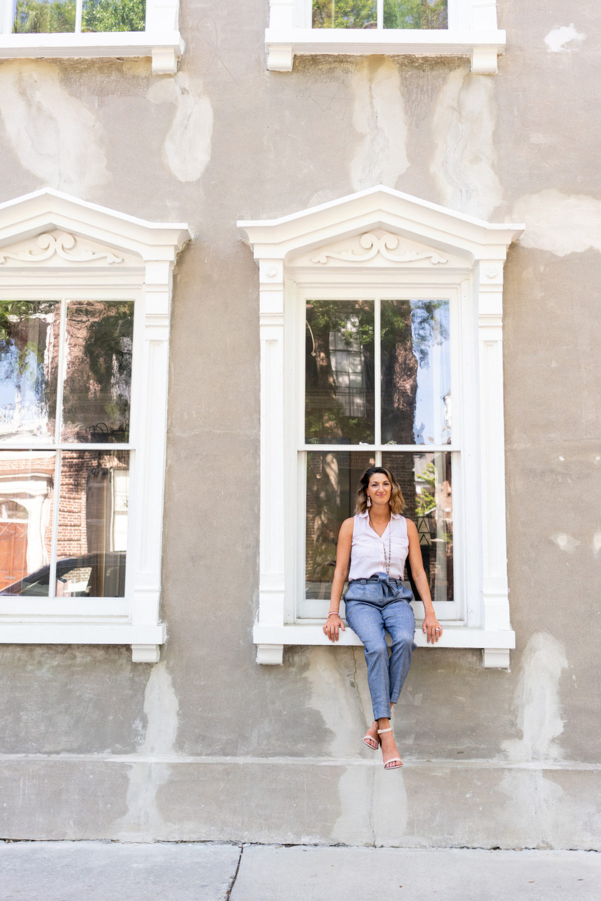 Woman sitting in a window of a historic house in Charleston, SC