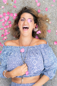 Woman laughing and surrounded by pink flower petals