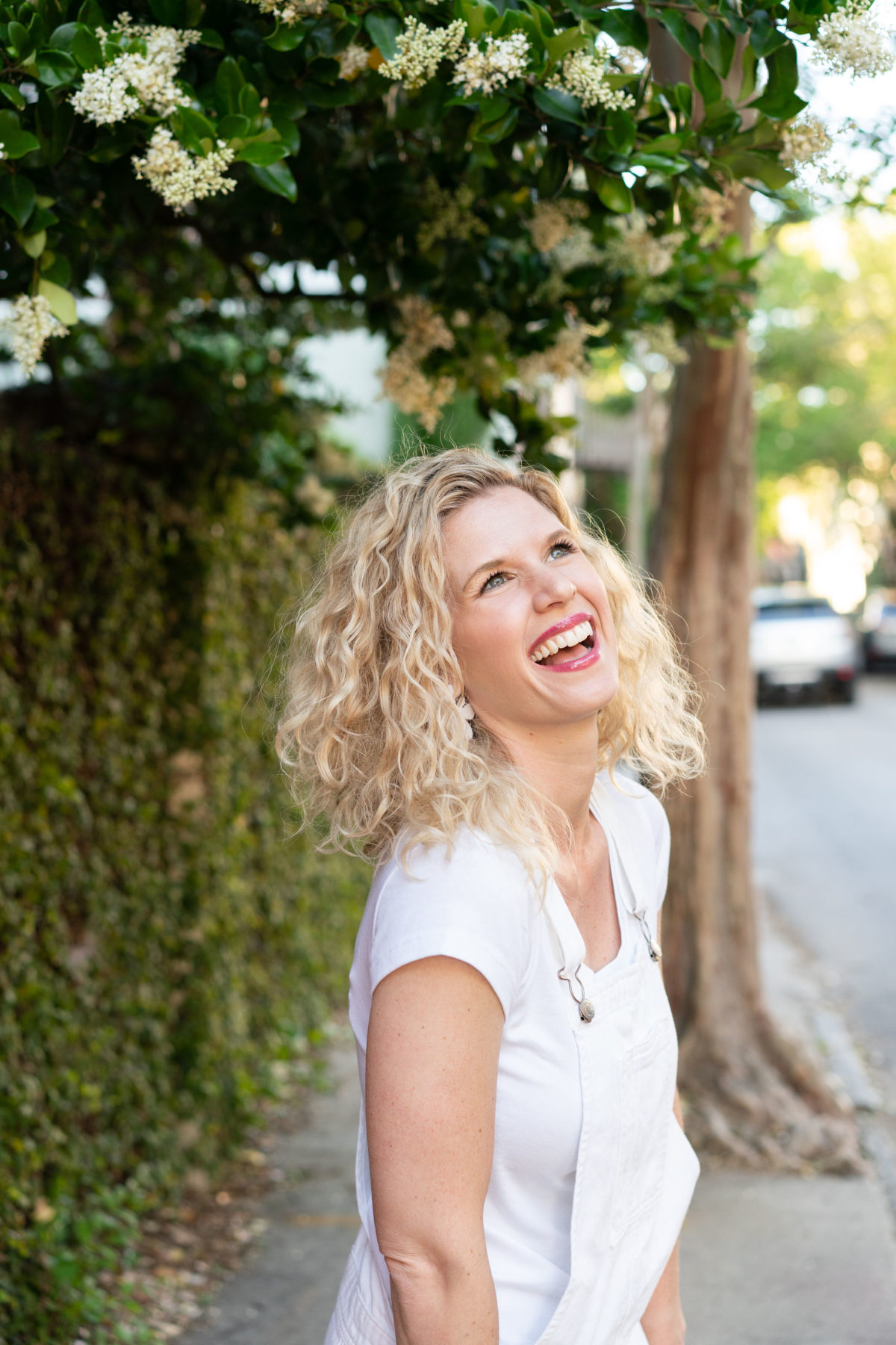 Woman in white denim overalls joyfully laughing