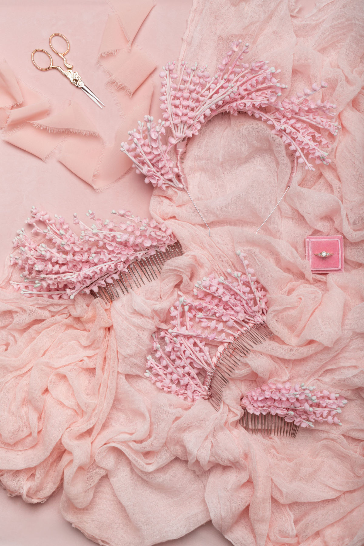 Flat lay of pink wedding headbands by Mariee Lace Veils on pink fabric