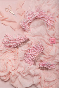 Flat lay of pink wedding headbands by Marie Lace Veils on pink fabric