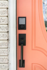 A Schlage Sense Smart Deadbolt and door handle on a coral front door