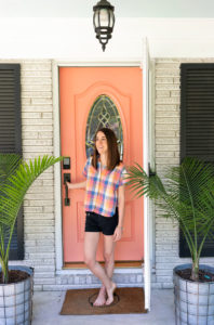 Woman in Madewell clothing standing by her brightly colored front door