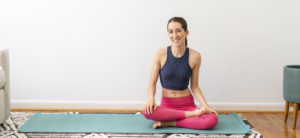 Woman sitting crossed-legged on yoga mat