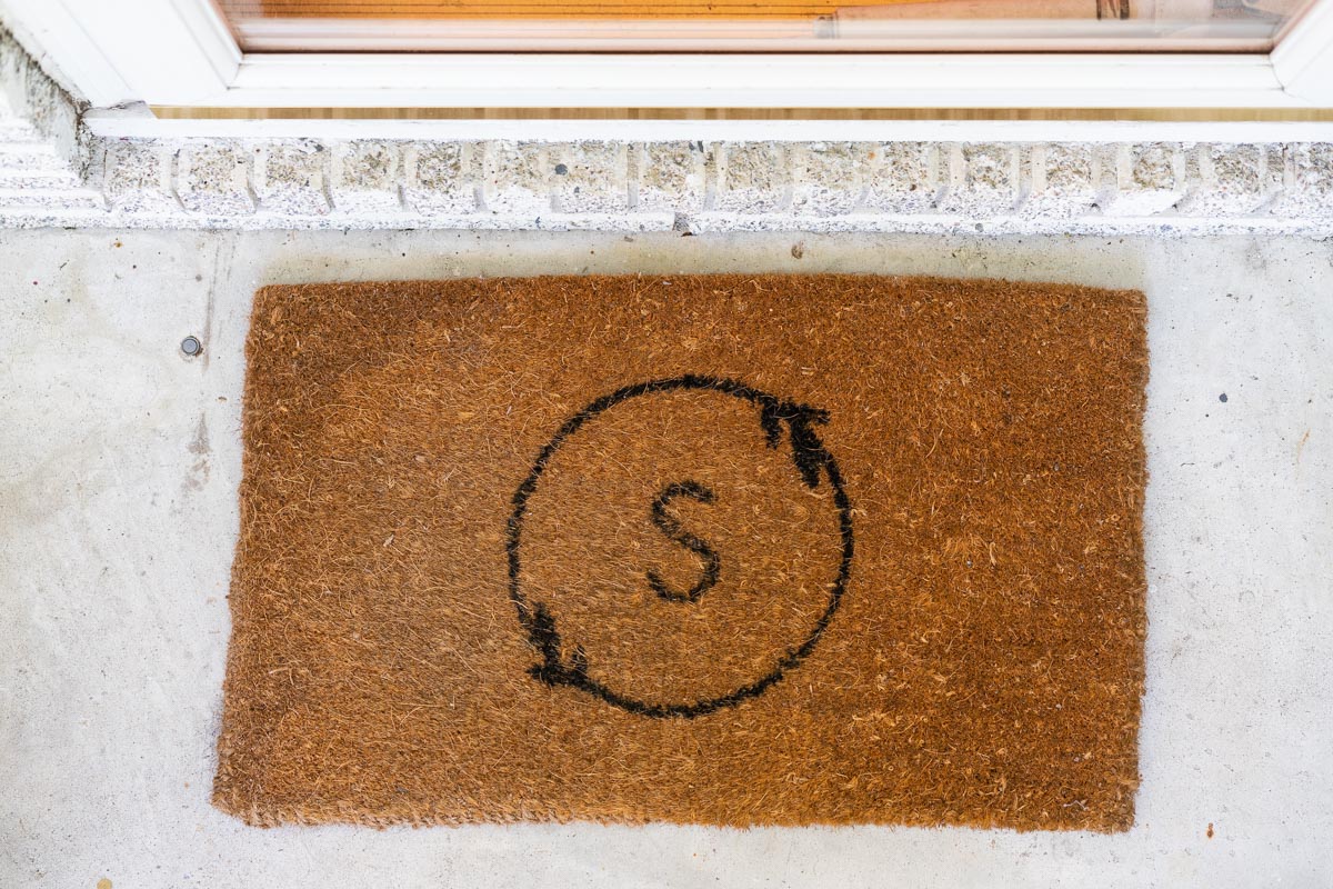 A West Elm doormat monogrammed with a circle with leaf details and an S