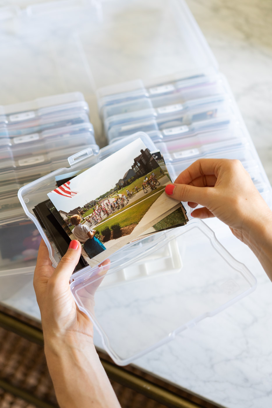 Hands sorting through a collection of family photos in a plastic protective case