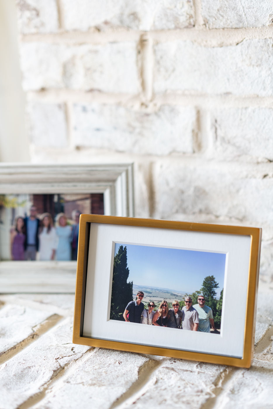 Two photo frames featuring family photos sitting on a white fireplace