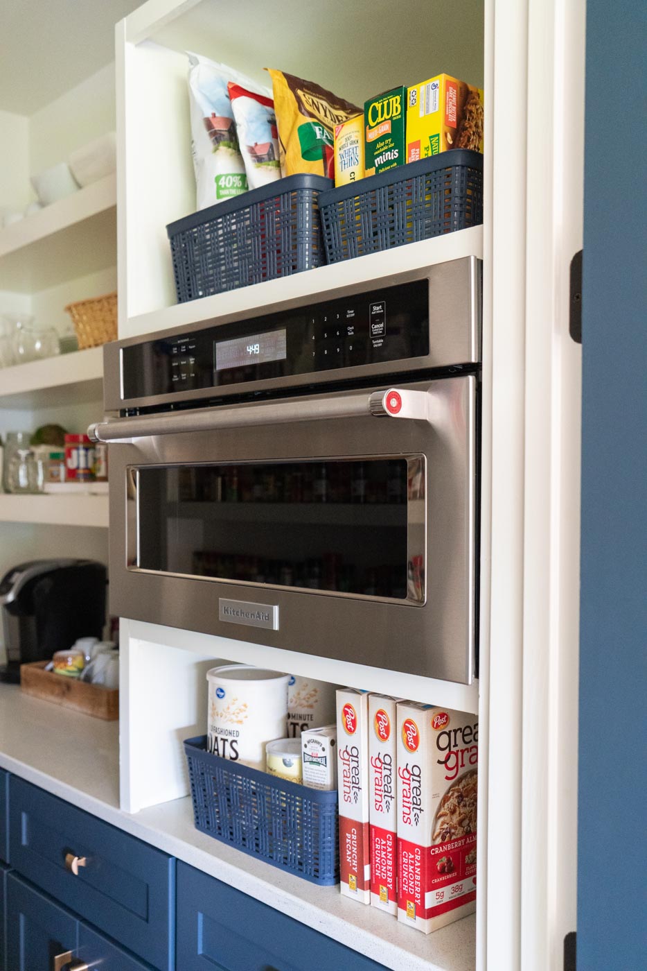 A KitchenAid microwave in a pantry with organized shelves