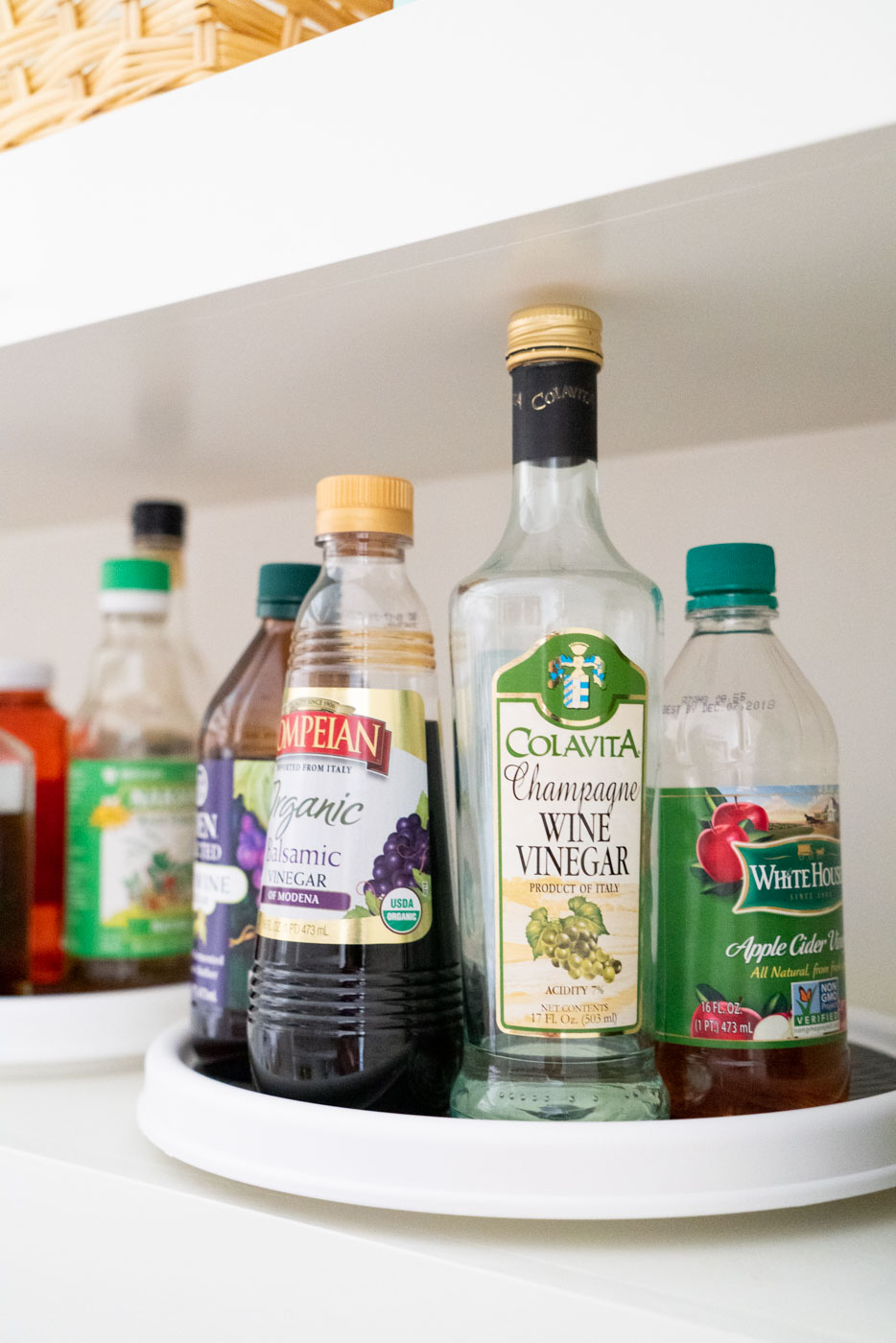 Vinegars on a lazy susan in an organized kitchen pantry